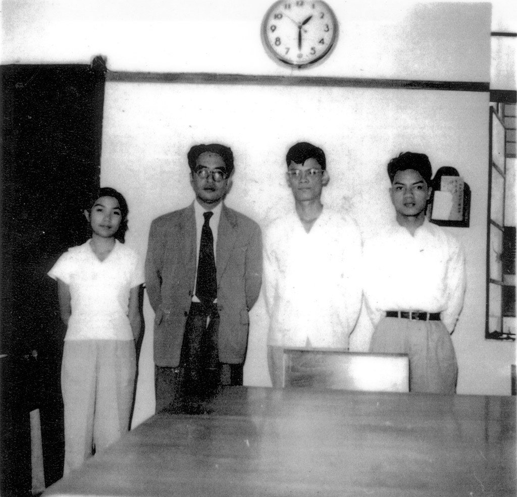 唐君毅先生與三位新亞同學攝於桂林街校舍教務處：（左起）古梅（55哲學教育學系）、唐君毅先生、唐端正（53哲學教育學系）、列航飛（53經濟系）